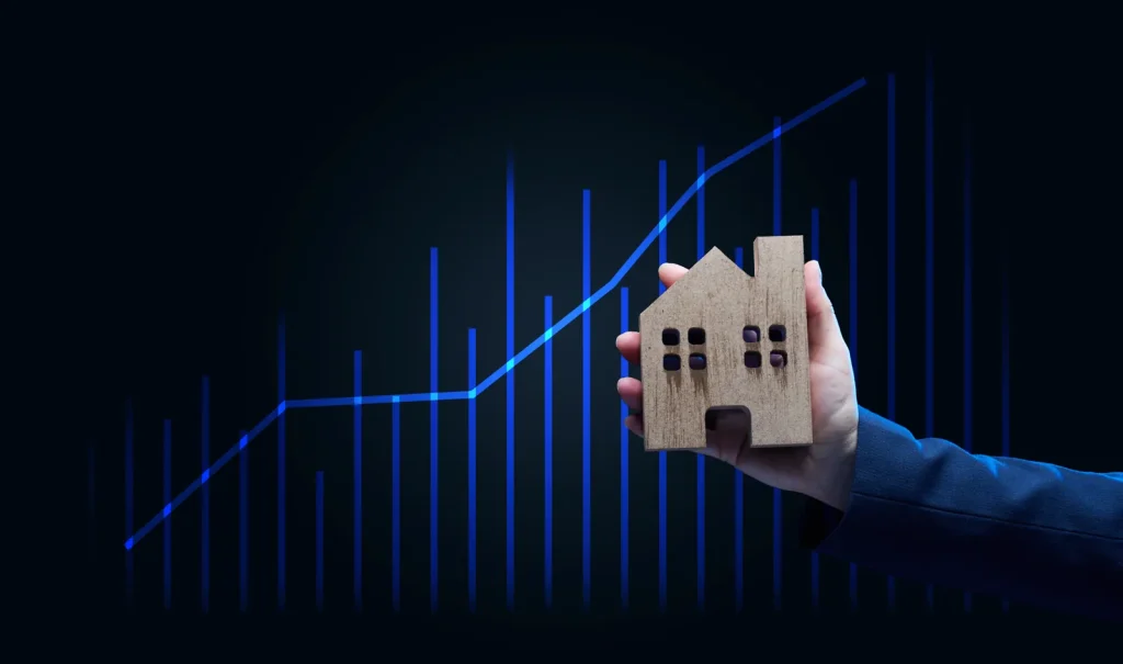 Maison miniature tenue devant une courbe de croissance, symbole du rendement locatif d'un investisseur